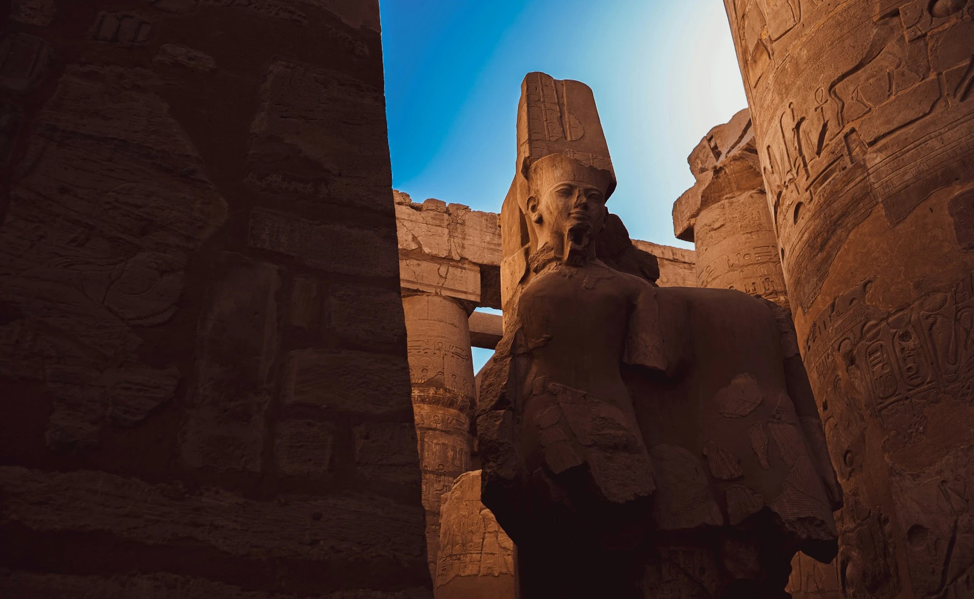 Statue monumentale d'un pharaon entre les colonnes massives du temple à Louxor